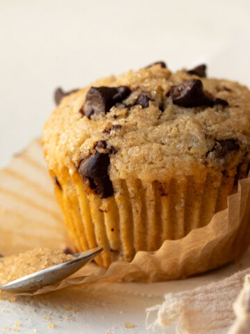 Close up of a muffin with the paper line partially peeled away.